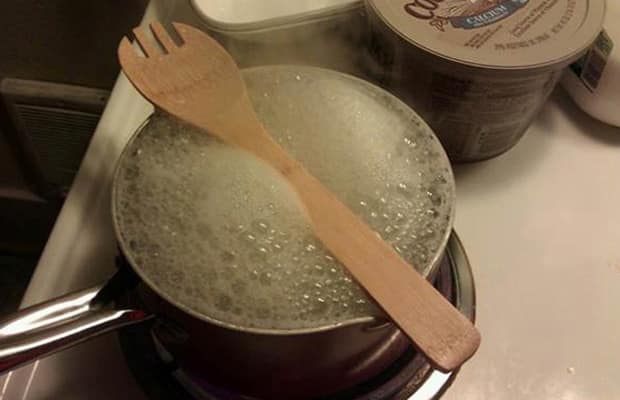 Wooden spoon placed horizontally on a boiling deep pan