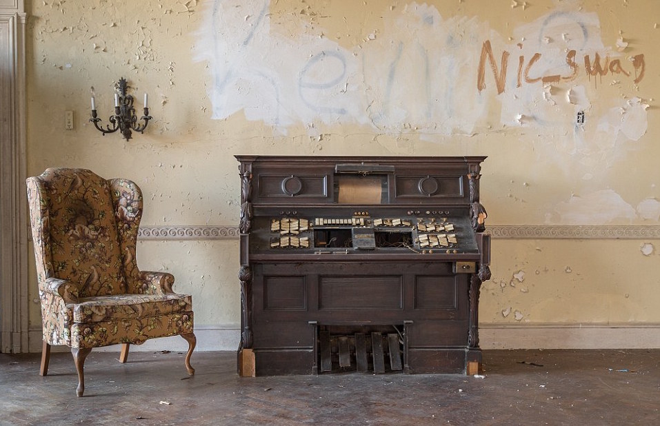 A Player Piano Sits Abandoned Next To A Chair